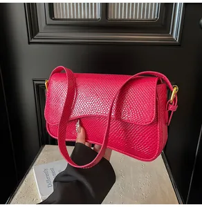 Détail d'un sac à main fuchsia gaufré lézard avec rabat et finitions métalliques dorées