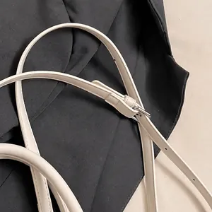 Detail of cream white adjustable shoulder strap with silver buckle and stitching
