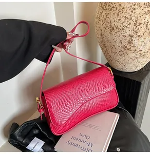 Détail du sac bandoulière rose fuchsia à motif serpent et boucles dorées porté par mannequin