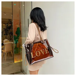 Detailed shot of transparent tote bag featuring 3D gold LOVE letters and brown inner pouch