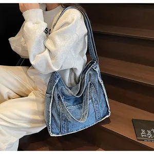 Detail of a large denim tote bag featuring frayed edges and multiple exterior pockets