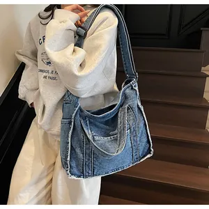 Detail of blue denim tote bag with frayed edges and dual handles for shoulder or hand carry