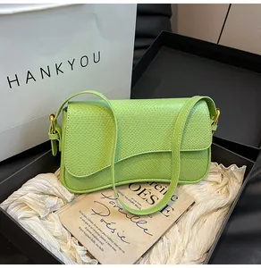 Détail du sac à bandoulière vert avocat à motif lézard dans un coffret cadeau noir