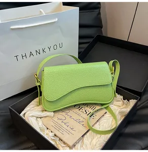 Détail d'un sac bandoulière vert clair en cuir texturé dans un coffret cadeau avec sac