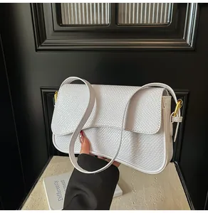 Gros plan sur un sac blanc gaufré effet crocodile avec anneaux en métal doré brillant