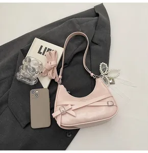 Detail of pink leather crescent bag with pearl bow charm and decorative lace straps