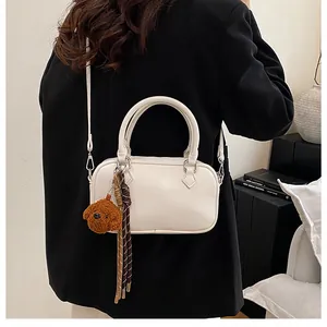 Close-up of white lychee pattern Boston bag with a cute brown teddy bear plush charm