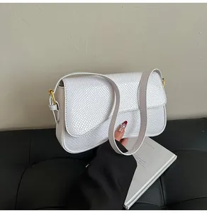 Gros plan d'un sac porté épaule en cuir gaufré blanc avec détails métalliques dorés