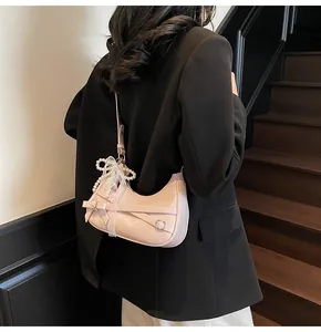 Close-up of pink crescent bag with pearl lace charm and leather bow detail