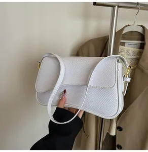 Détail du sac sous l'aisselle à texture peau de serpent blanche avec boucle dorée chic