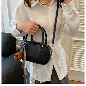 Close-up of black lychee grain boston bag with cute bear charm on lace shirt