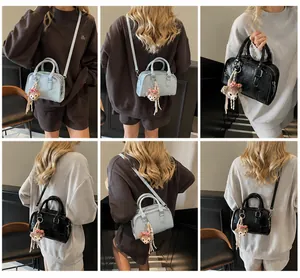 Model showcasing a textured blue Boston bag with handles and a bear charm accessory