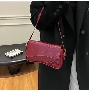 Gros plan du sac à bandoulière bordeaux motif lézard avec détails dorés sur modèle