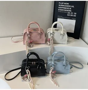 Detail of Boston bags in pink, white, grey, and blue with embossed logo and plush bear charm