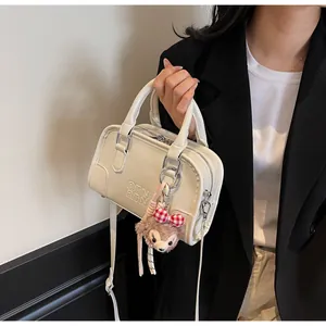 Macro view of cream leather handbag with embossed letters and a bear charm detail