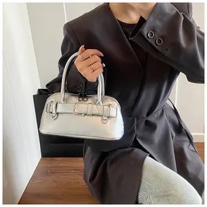Close-up of metallic silver shell bag with horizontal strap buckle and sleek handles