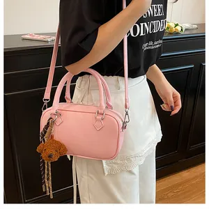 Detailed shot of pink litchi grain leather Boston bag with a cute brown teddy bear charm