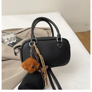 Close-up of black lychee texture Boston bag with cute plush bear and woven pendant charm