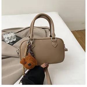 Detail of khaki Boston bag with Saffiano texture and cute brown teddy bear charm accessory