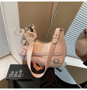 Close-up of pink crescent hobo bag with pearl chain, lace bow and silver heart charm
