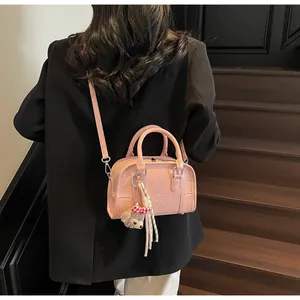 Pink embossed Boston bag featuring a plush doll charm and chic crossbody strap
