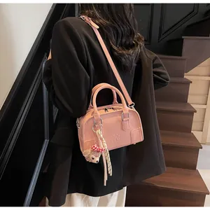 Detail of pink faux leather Boston bag featuring embossed letters and a plush bear charm