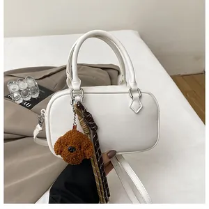 Close-up of white lychee pattern Boston bag with cute plush puppy charm and strap