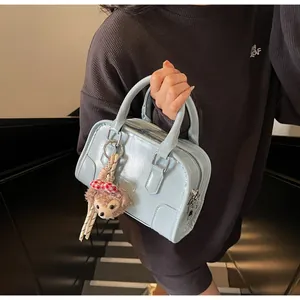 Detail of light blue boston bag with embossed letters and plush bear charm