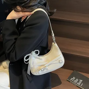 Creamy white hobo crescent bag with lace bow and pearls on a model in black blazer