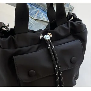 Detailed view of black nylon bucket bag featuring a drawstring closure and buckle pocket