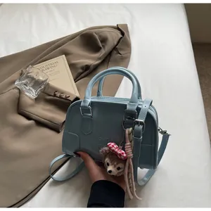 Light blue crossbody bag with embossed letters and a cute plush character charm