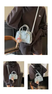 Close-up of light blue mini Boston bag with embossed letters and plush bear charm