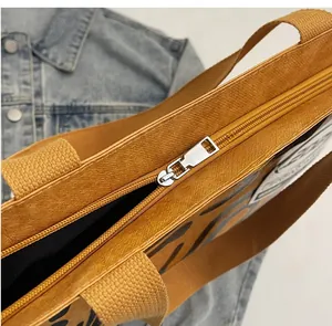 Detail of smooth metal zipper and wide woven strap on mustard yellow tote bag