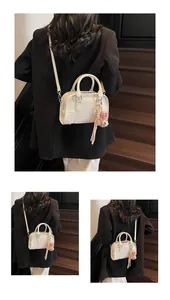 Back view of model carrying a white embossed mini Boston bag on a wooden staircase