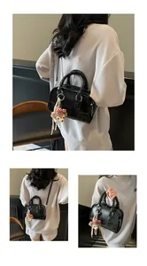 Detail view of black Boston bag with silver hardware and plush bear charm accessory