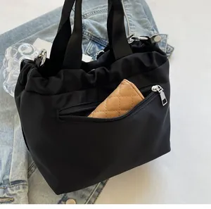Detailed view of black nylon drawstring bucket bag with a beige wallet in the front pocket