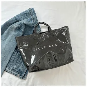 Vista dall'alto di una borsa tote nera lucida con scritta TOTE BAG su tessuto bianco