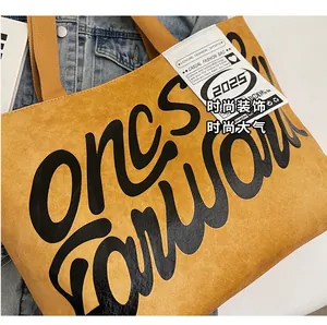 Detail of yellow tote bag with black letter print and texture on casual fabric