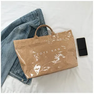 Dettaglio borsa tote in carta marrone con strato in PVC e scritta TOTE BAG bianca