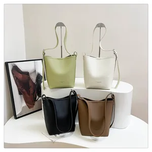 Detail view of four lychee grain leather bucket bags in green, white, black and brown