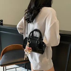 Glossy black Boston handbag with plush charm and detachable strap for women