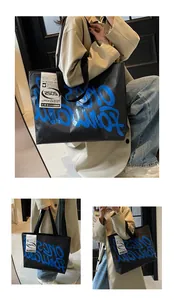 Detail view of large black tote bag with blue graffiti text and industrial white label