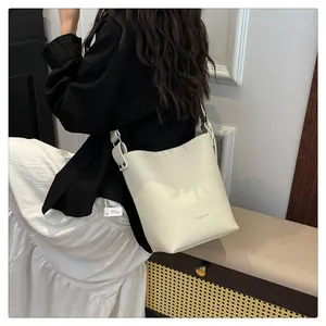 Detail of cream lychee texture leather bucket bag with wide strap on model back