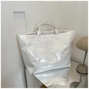 Vista dettagliata della borsa tote in carta stropicciata crema con finitura lucida e testo