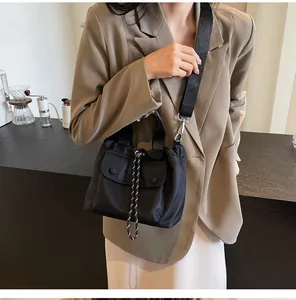 Detail of black nylon bucket bag featuring drawstring closure and striped shoulder strap