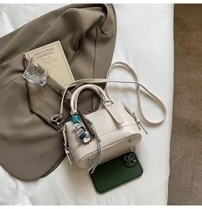 Detail shot of a cream-colored leather handbag with fine textures and a bear charm accessory