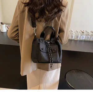 Detail of a black nylon drawstring bucket bag with snap pockets on a brown blazer outfit