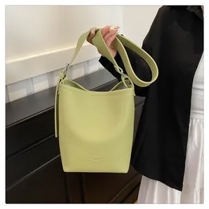Detail view of light green lychee texture leather bucket bag with embossed lettering