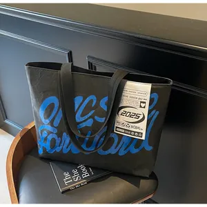 Detail of waterproof black tote bag featuring blue graffiti text on wrinkled fabric