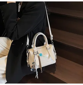 Detail of off-white Boston handbag with embossed texture and trendy beaded charm